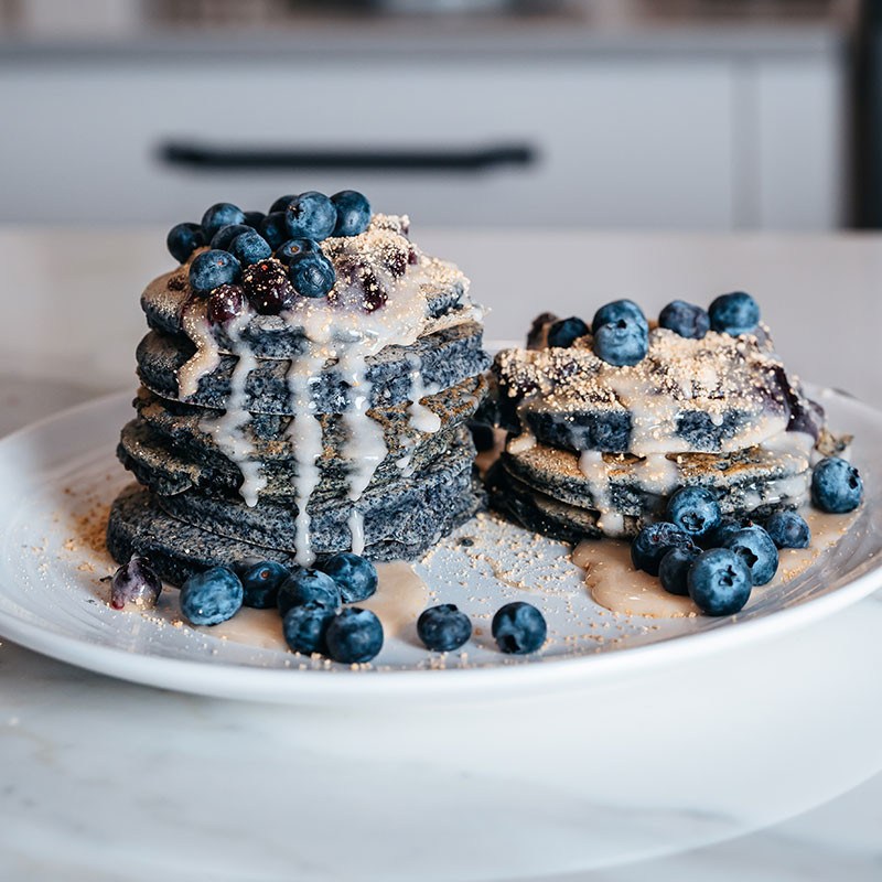 Blueberry cheesecake pancakes topped with blueberries and cream